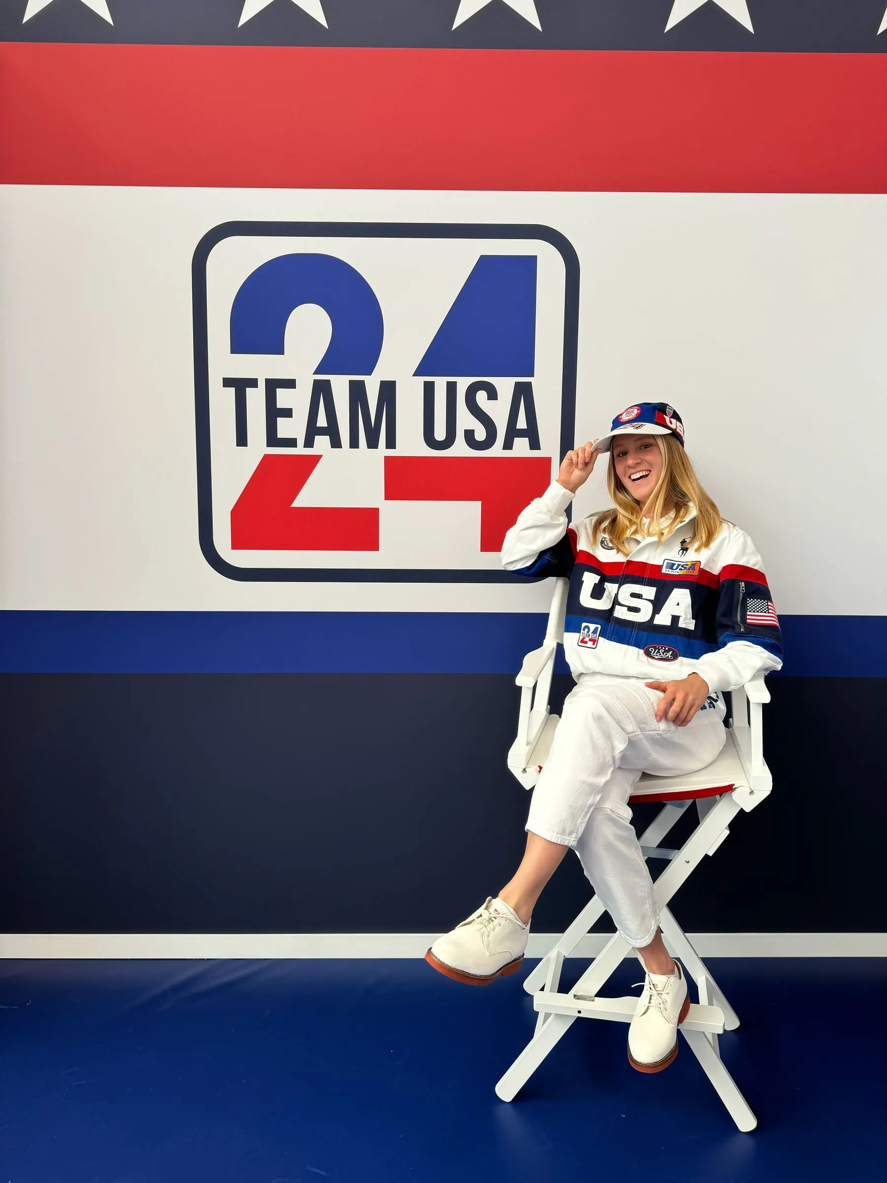 Leah Crouse sits in a director's chair in front of a Team USA backdrop.